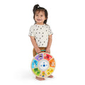 Criança a segurar o brinquedo musical Hape Baby Einstein Orquestra Magic Touch pela pega de transporte.