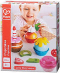 Caixa do Hape Conjunto Cupcakes de madeira com criança a brincar, mostrando as 18 peças coloridas para faz de conta.
