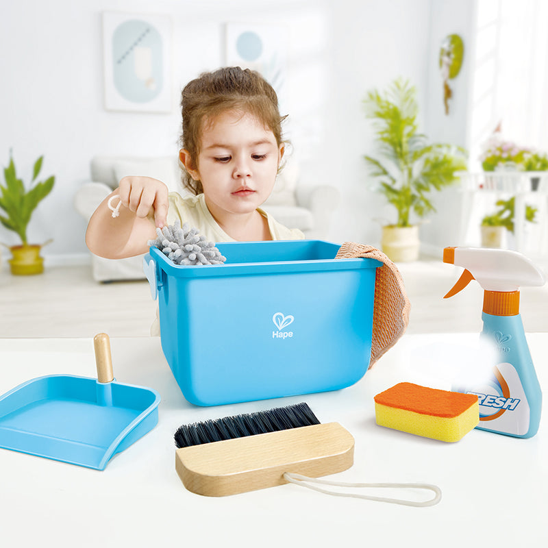 Menina a brincar com o conjunto de limpeza Hape, usando o espanador para limpar, promovendo a imitação e a diversão.