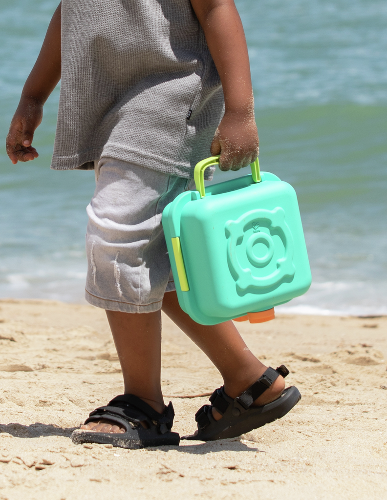 Criança a transportar a mala de cozinha de praia Hape na mão.