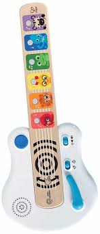 Bebé a interagir com a guitarra Hape Magic Touch, tocando nas cordas, destacando a pega ergonómica e o uso lúdico.