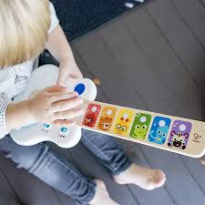 Vista lateral da guitarra Hape Baby Einstein, mostrando o painel de controlo com o botão de ativação de música e os 3 níveis de som ajustáveis.