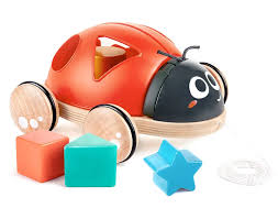 Joaninha Hape de madeira com corpo vermelho, rodas de madeira e 4 formas geométricas coloridas (quadrado, triângulo, estrela) em primeiro plano.