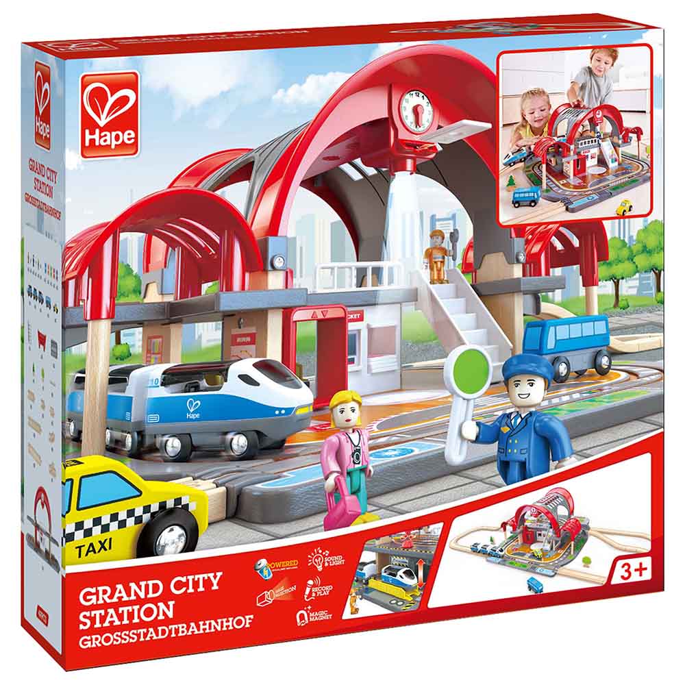 Caixa do Hape Mega Kit Construção cidade e estação comboios, mostrando a estação, comboio, táxi e figuras de brincar.
