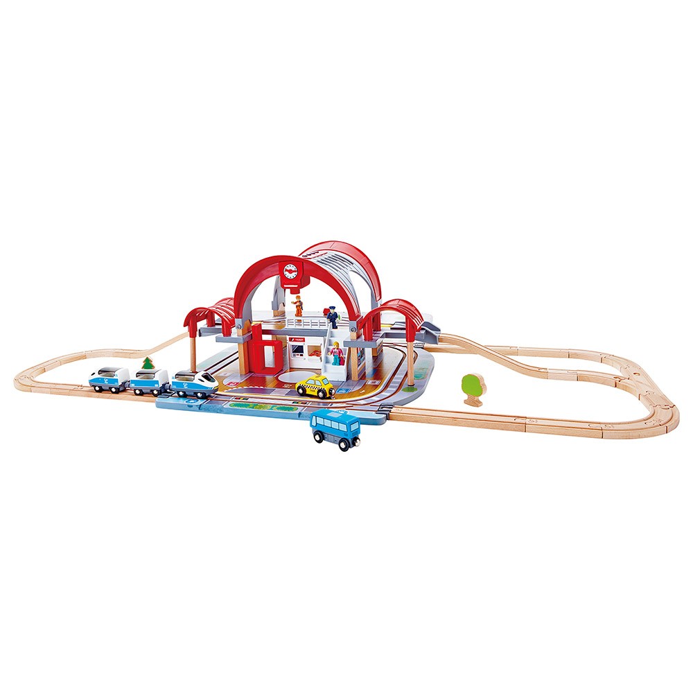 Vista geral do conjunto Hape Mega Kit Construção Estação Comboios montado com trilhos, comboio, autocarro e táxi.