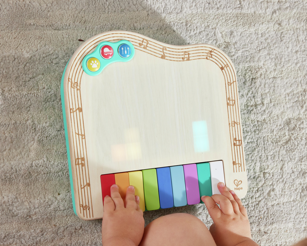 Maos de bebe a tocar nas teclas do piano Hape Pixel.