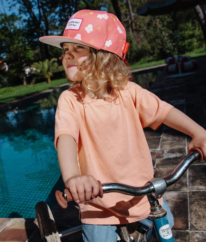 Boné infantil Hello Hossy Peach Blossom em tons suaves de pêssego com pala plana e fecho ajustável.