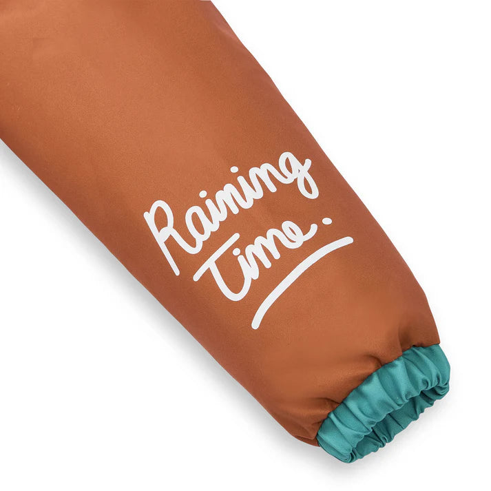 Detalhe da manga do casaco impermeável Hello Hossy, mostrando a inscrição branca "Raining Time" e o forro do punho em verde-água.