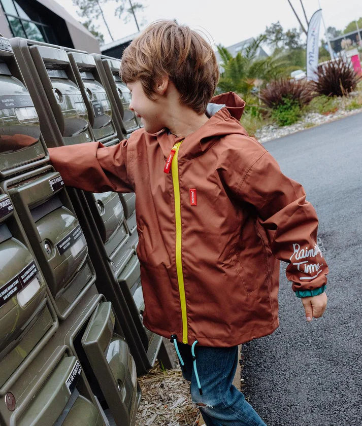 Criança a interagir com caixas de correio, exibindo o Casaco Peanut impermeável da Hello Hossy, ideal para exploração ao ar livre.