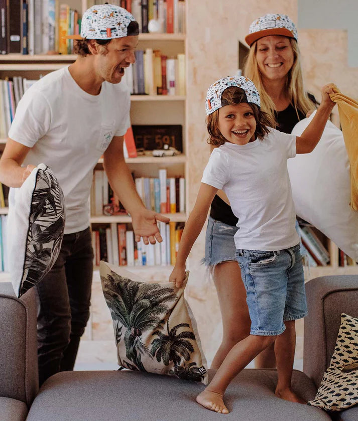 Família (pai, mãe, filho) usa bonés Hello Hossy Aussie a brincar, mostrando tamanhos criança e adulto.