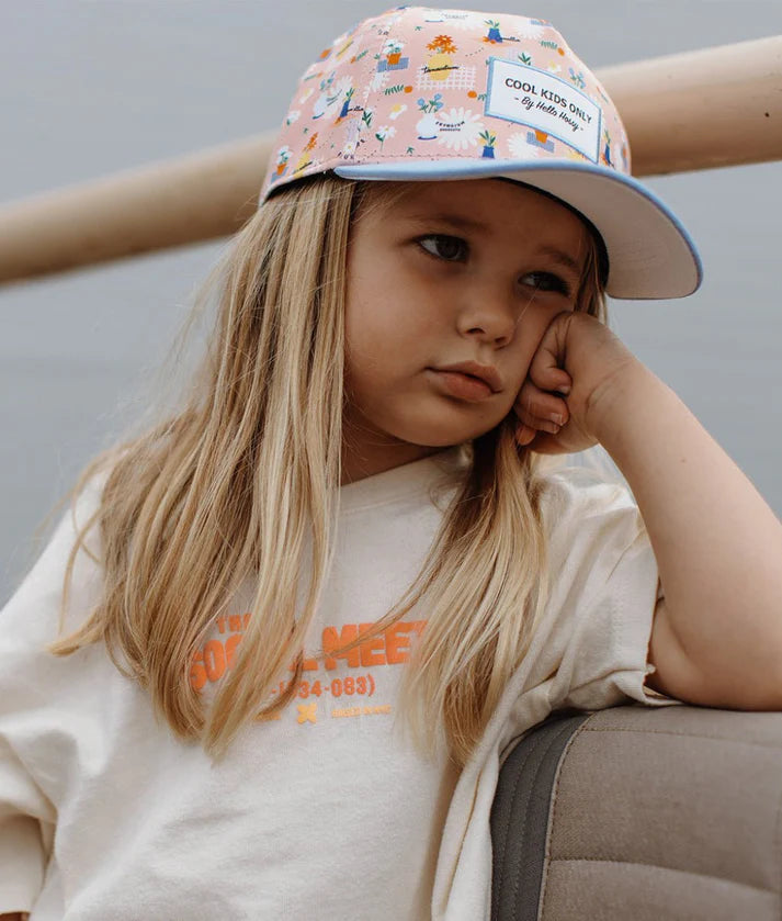 Criança usando boné Flore Hello Hossy com padrão floral. Acessório de moda infantil estiloso e confortável.