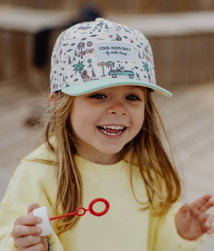 Close-up de menina a usar boné Hello Hossy Jungly, mostrando o estampado e o patch "Cool Kids Only".