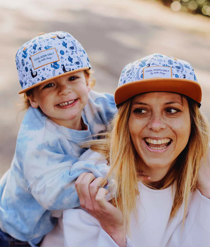 Mãe e criança sorridentes com bonés Hello Hossy Lama a condizer. Estilo divertido para família.