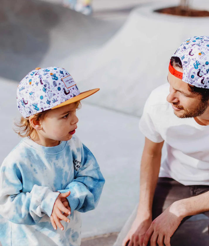 Pai e filho com bonés Hello Hossy Lama a condizer, em conversa. Look familiar.