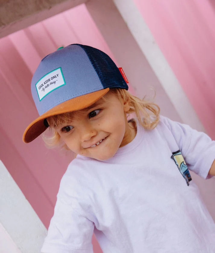 Criança bebé sorridente usa boné Hello Hossy Marine azul/laranja. Confortável e ajustável para crescer.