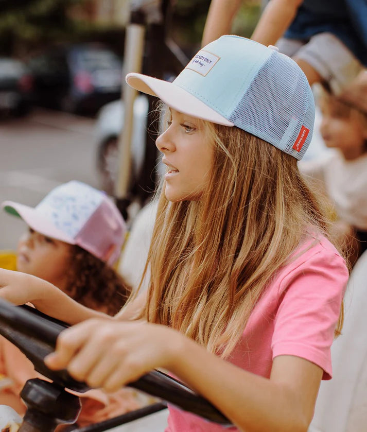 Girl wearing Hello Hossy boné Mini Lagoon azul e rosa, estilo trucker, em uso.