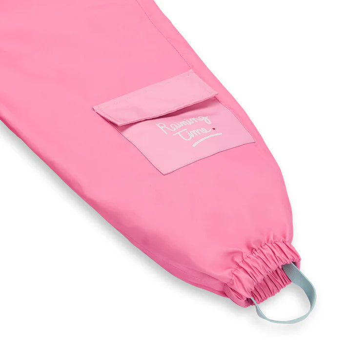 Detalhe do bolso lateral do macacão rosa Hello Hossy, com inscrição "Raining Time" e bainha elástica.