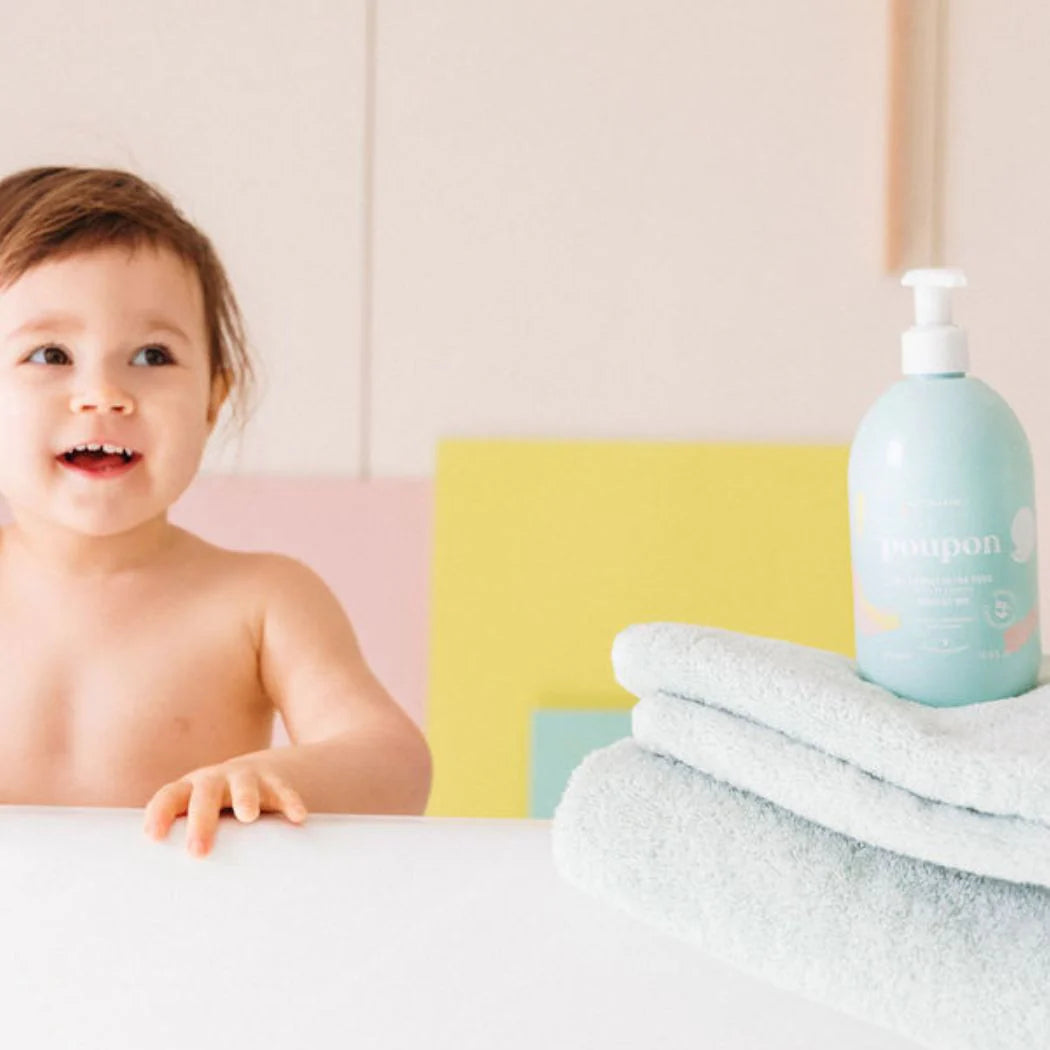 Bebé no banho rodeado por produtos de higiene infantil suaves e naturais.