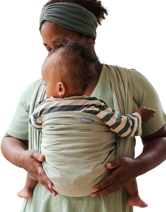 Mãe com turbante verde a usar o pano tecido Hoppediz T6 ELBA, segurando um bebé de costas com padrão às riscas.