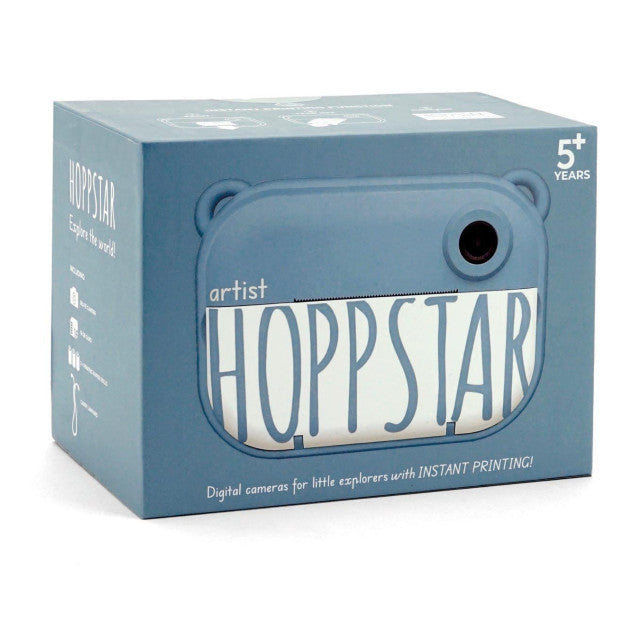 Caixa do produto Hoppstar Artist, azul, com a imagem da câmara e indicação de 5+ anos e impressão instantânea.