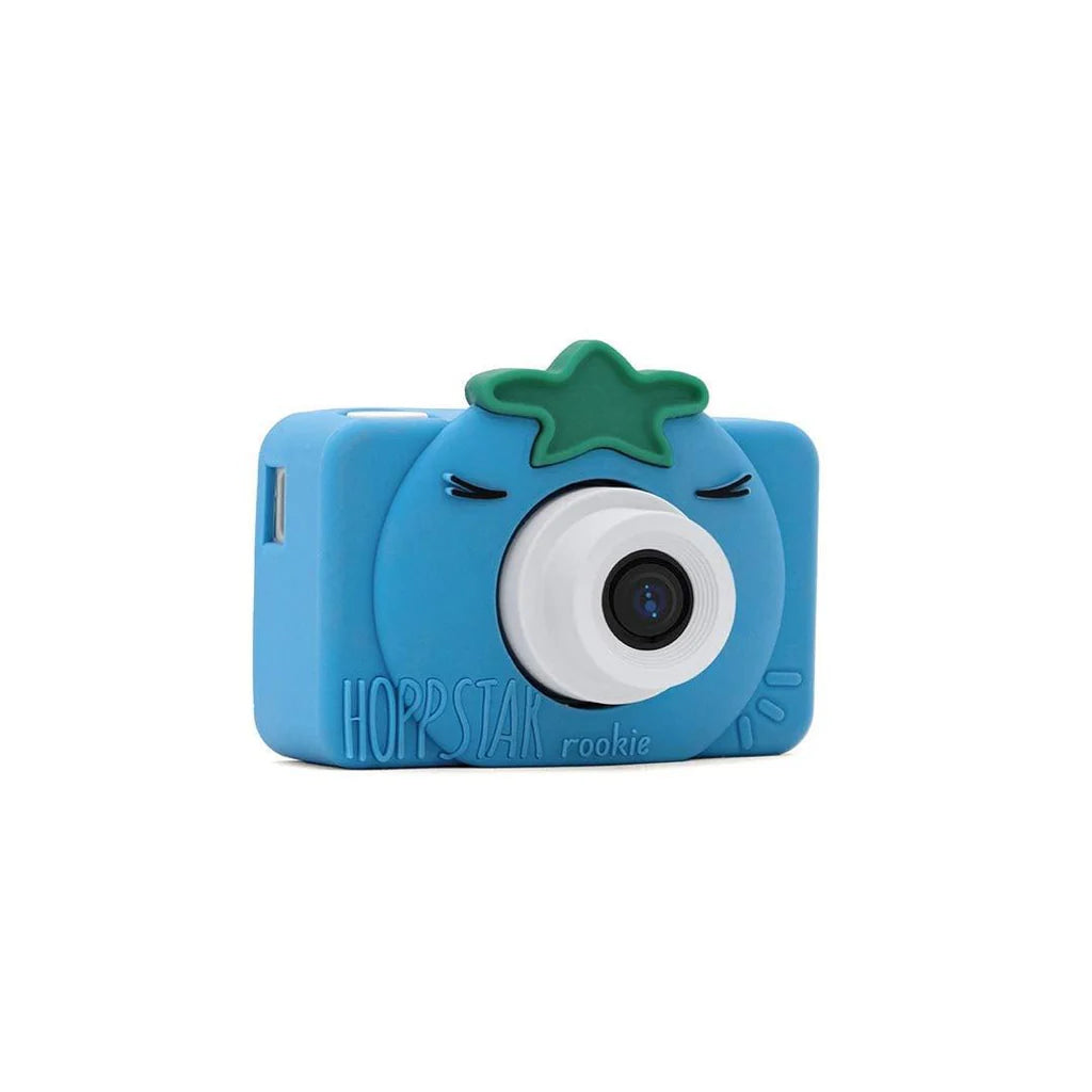 Máquina fotográfica digital Hoppstar Rookie Bluebelle em perspetiva, destacando a lente, a capa de silicone azul e o detalhe da estrela verde.