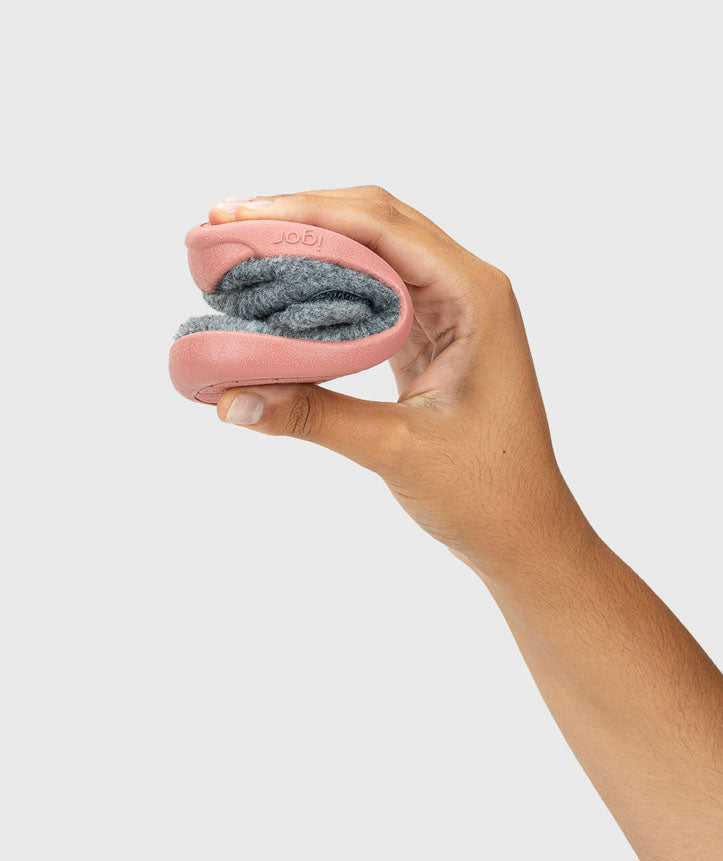 Demonstração da flexibilidade da pantufa Igor HOMIE, dobrada ao meio, mostrando a sola rosa e o interior cinza.