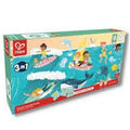 Embalagem do Hape Puzzle 3 em 1 Oceano, com o logótipo Hape e ilustrações vibrantes de cenas de praia e mar.