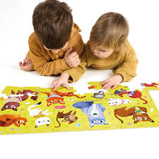 Duas crianças pequenas deitadas no chão a montar o puzzle Banana Panda I Love Cats, focadas nas peças.