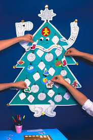 Mãos a decorar uma árvore de Natal gigante feita de poster, adicionando enfeites coloridos e recortados.