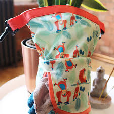 Saco impermeável multiusos Pop In da Close, com padrão de orangotangos, segurado à mão, mostrando o fecho enrolado e um pequeno bolso exterior com fecho laranja, onde se vê um pedaço de tecido.