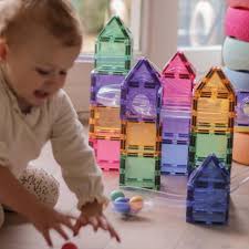 Criança mais nova a interagir com estruturas altas de blocos magnéticos Clever Clixx cor de pastel, focada em apanhar as bolas que descem.