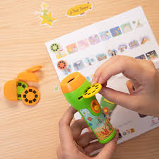 Detalhe de uma mão a inserir um dos discos de projeção no projetor, com o manual de instruções ao fundo.