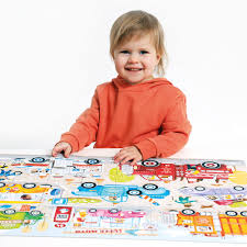 Criança sorridente a interagir com o puzzle gigante Banana Panda Primeiro Puzzle Jumbo – Cars, mostrando o tamanho real do produto.