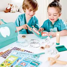 Duas crianças a brincar com o Hape Conjunto Dentista, praticando higiene oral no modelo de boca e explorando os instrumentos.