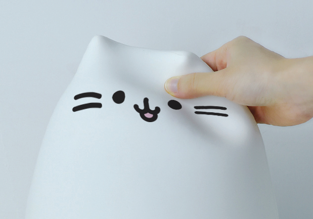 O gatinho de luz noturna InnoGio ao lado de um cabo USB, pronto para ser carregado, mostrando o seu tamanho compacto.