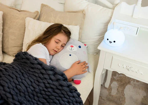 Linha de várias luzes de presença de silicone InnoGIO (incluindo o cão, panda e unicórnio) acesas com cores diferentes sobre uma superfície tricotada.