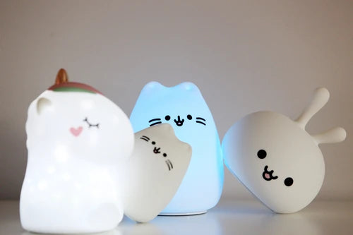Três luzes de presença InnoGio de silicone: um gatinho com gorro, um gatinho azul a mudar de cor e uma figura de coelho, em exposição.