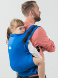 Vista traseira da criança sendo carregada nas costas pelo pai com a mochila Isara Toddler Preschooler IRIS BLUE BAMBOO.