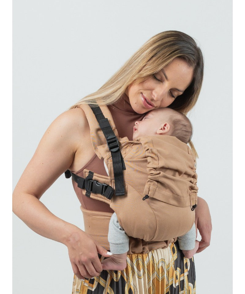 Mulher a usar a Mochila ISARA The ONE Ajustável MACCHIATO na posição de transporte frontal, com um bebé acordado.