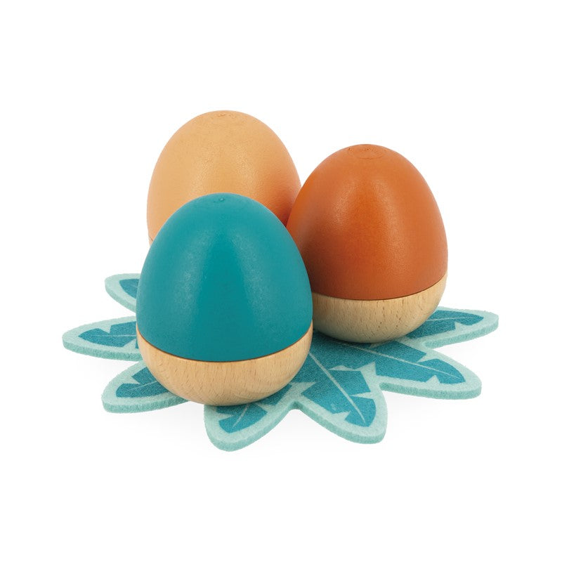 Três ovos de madeira Janod de diferentes cores sobre a base de feltro.