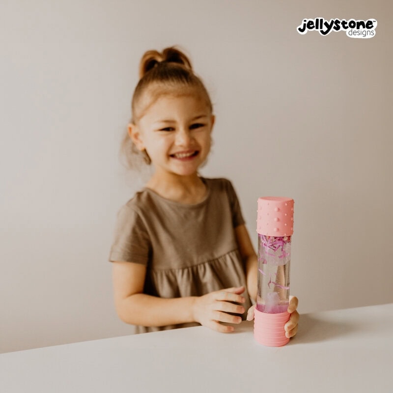 Criança sorridente com a Garrafa da Calma DIY Rosa Jellystone, destacando a alegria e o bem-estar proporcionados.