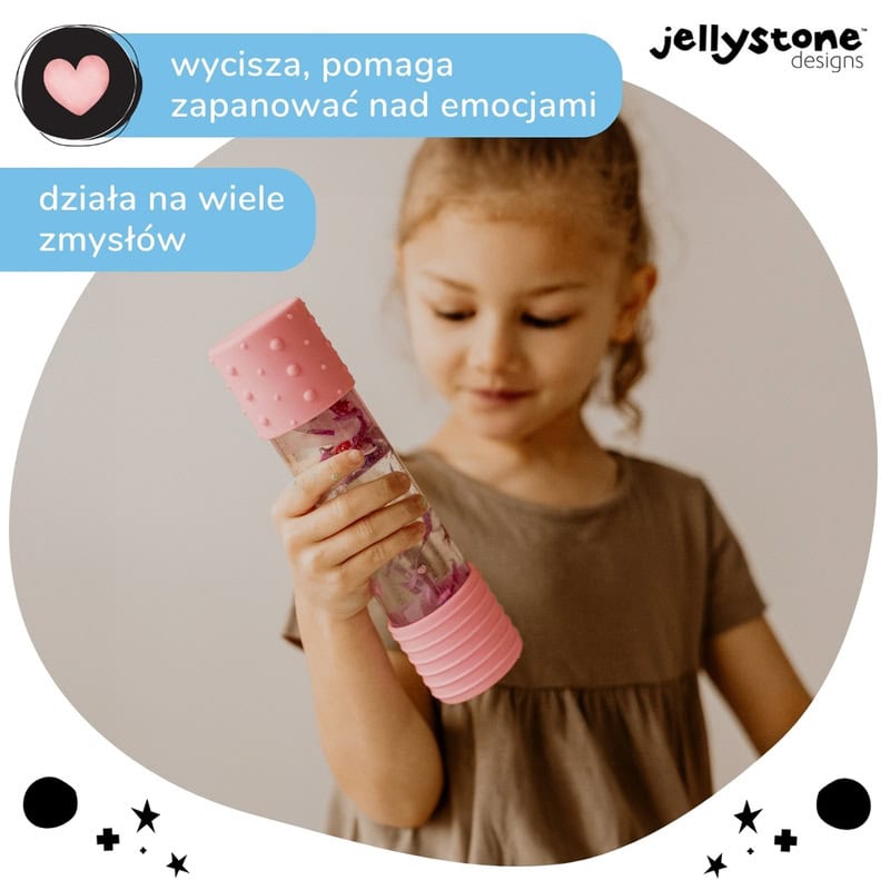 Menina a segurar a Garrafa da Calma DIY Rosa Jellystone, focada nos elementos flutuantes. Promove tranquilidade e concentração.