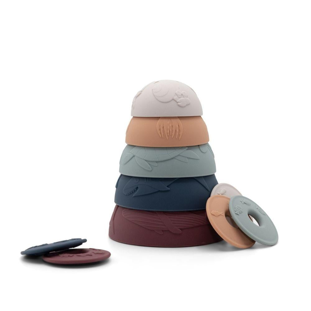 Pirâmide empilhada de 5 taças sensoriais Jellystone em tons terrosos e oceânicos, com moedas do tesouro ao lado.