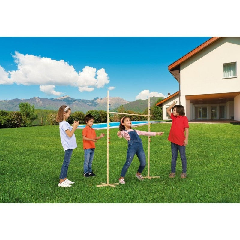 Quatro crianças a brincar ao Jogo de Limbo no jardim, com uma menina a tentar passar por baixo da vara.