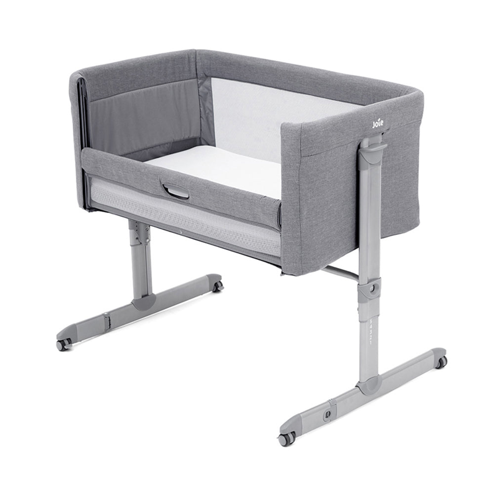 Berço de viagem Joie Roomie cinzento, ligeiramente inclinado, mostrando o interior com colchão e estrutura ajustável com rodas.