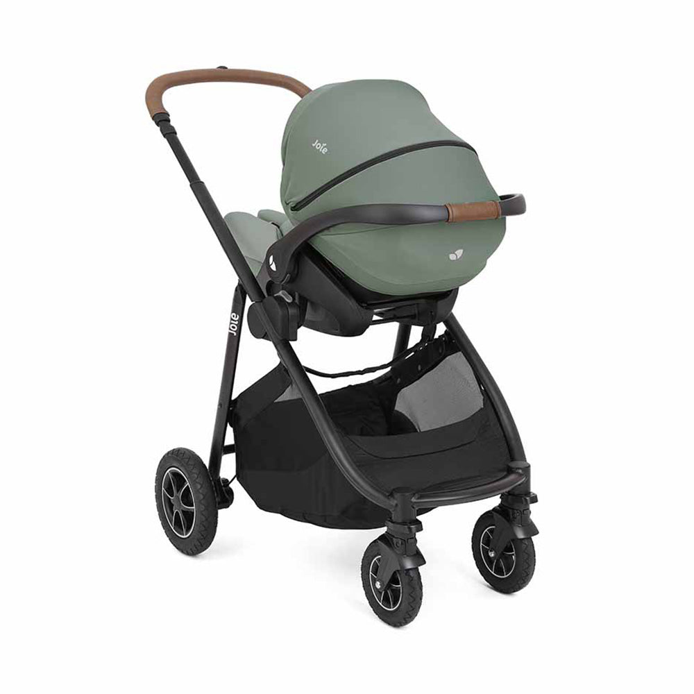 Carrinho Joie Versatrax™ com capa de chuva transparente instalada, protegendo o assento.