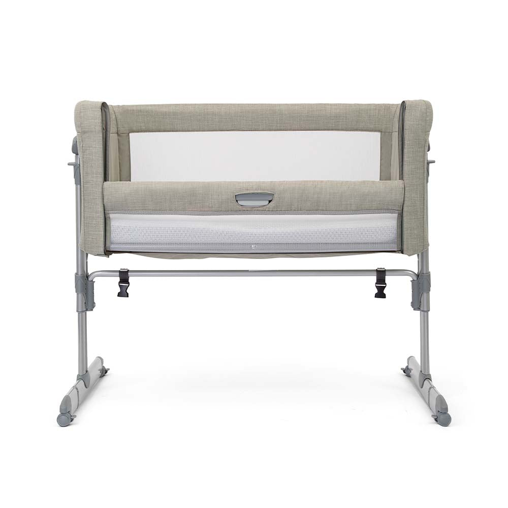Berço Co-Sleeper Joie Roomie Glide em cor neutra, montado ao lado de uma cama de casal, com a lateral rebatida para acesso fácil ao bebé.