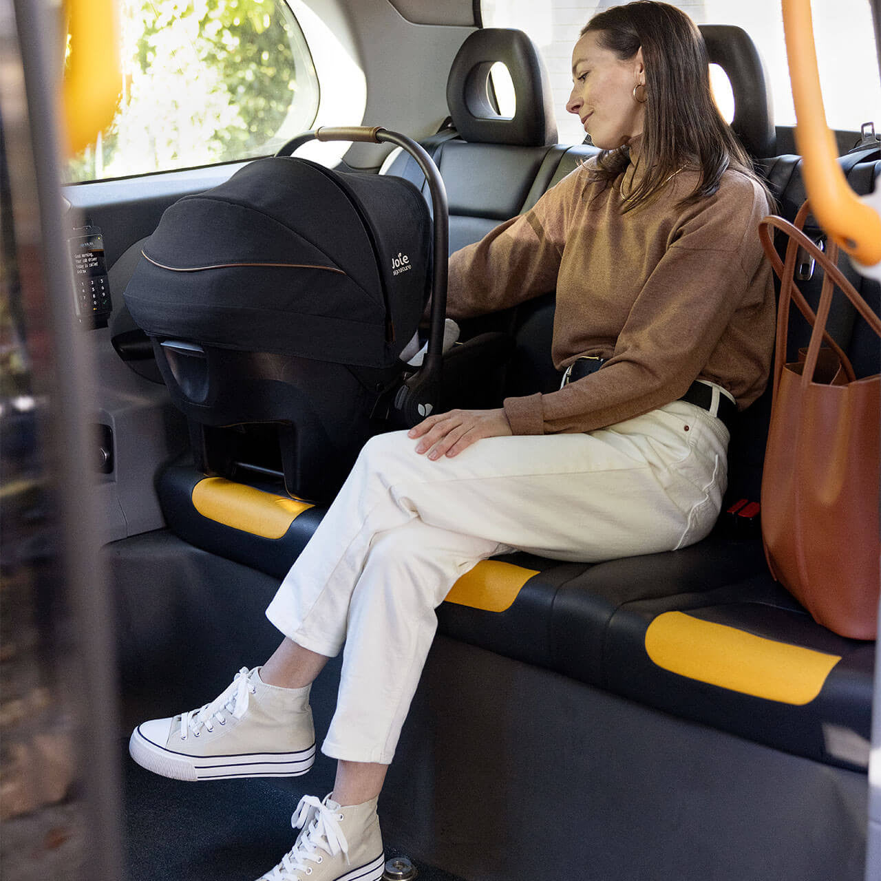 Uma mulher ajusta a cadeira auto Sprint no banco de trás do veículo, demonstrando a instalação fácil e segura com conectores ISOFIX.