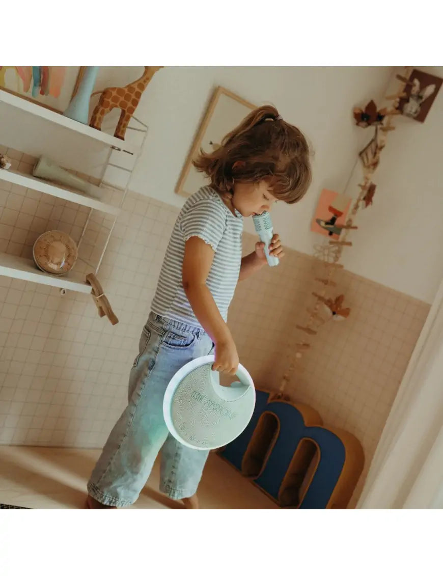 Menina a transportar facilmente a coluna KidyWolf Karaoke Kidy pela pega enquanto canta, demonstrando a sua portabilidade.