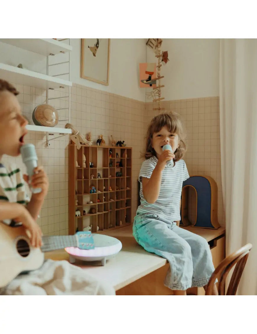 Duas crianças, um menino e uma menina, a divertirem-se a cantar em dueto com os dois microfones do KidyWolf Karaoke Kidy.